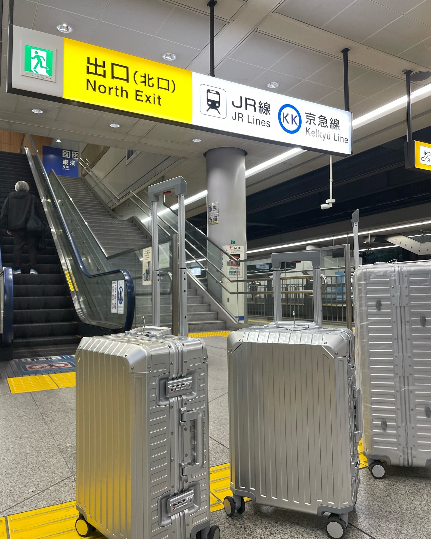 Silver aluminum suitcases with a sleek hard shell, TSA-approved locks, and smooth spinner wheels, positioned in a modern train station, ideal for business and luxury travel.